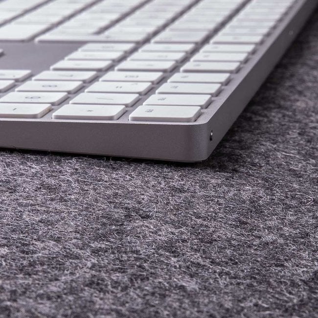 Close-up of white keyboard on textured grey wool felt desk mat