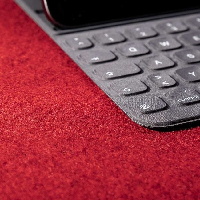 Black tablet keyboard on rich red wool felt desk pad