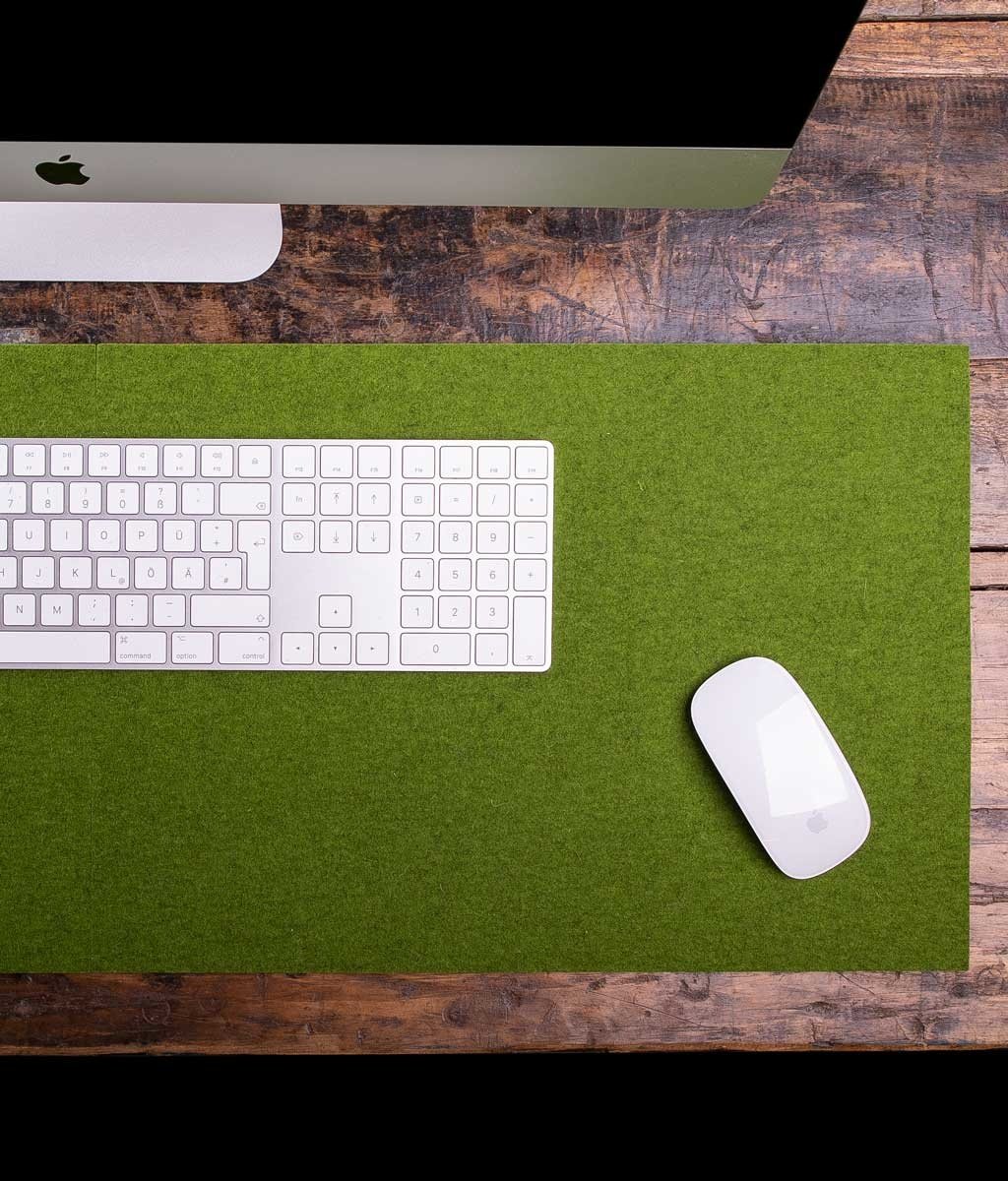 White Apple keyboard and mouse on green wool felt desk pad over rustic wooden table