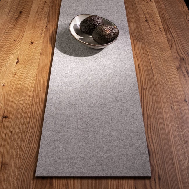 Light grey wool felt table runner with metal fruit bowl on wood dining table