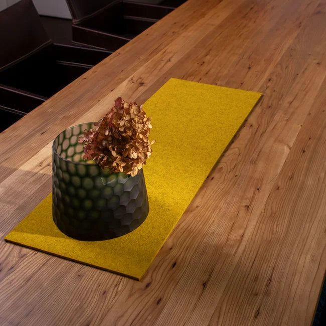 Mustard yellow wool felt table runner with potted plant on wood table