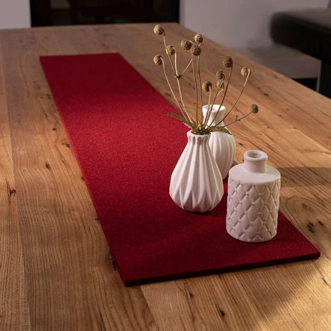 Red wool felt table runner with wine glasses on wooden dining surface