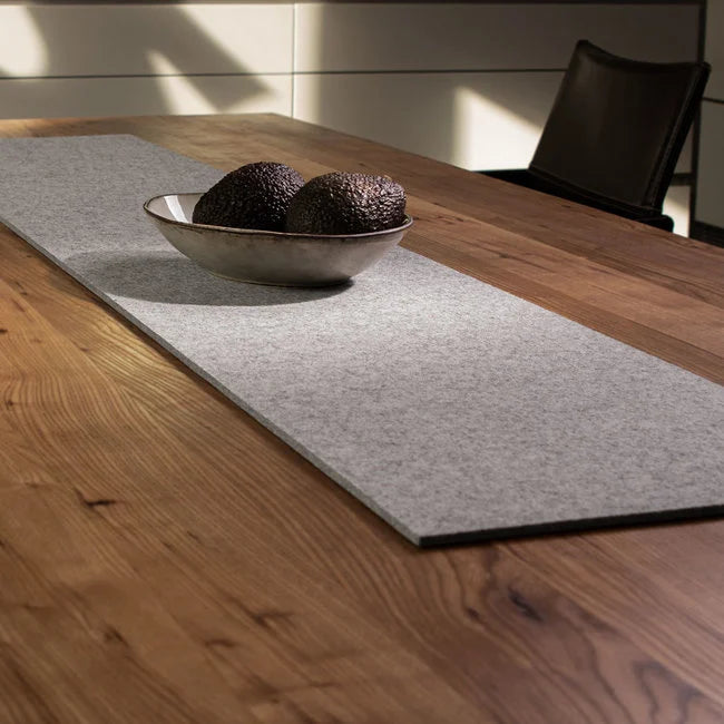 Light grey wool felt table runner with ceramic bowl on wooden dining table
